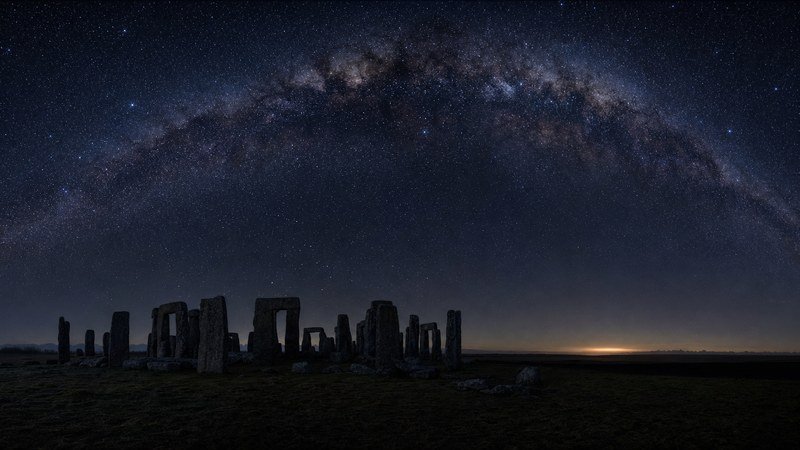 Il cerchio di pietre di Stonehenge di notte, con l'arco della Via Lattea che attraversa il cielo sopra