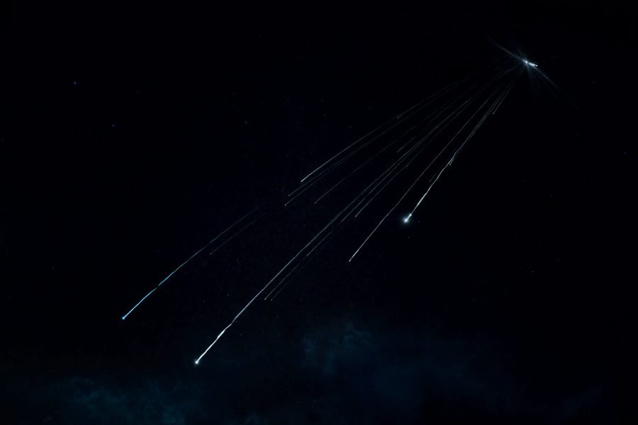 Varias estrellas fugaces cruzando un cielo negro, con todas sus estelas saliendo del mismo punto